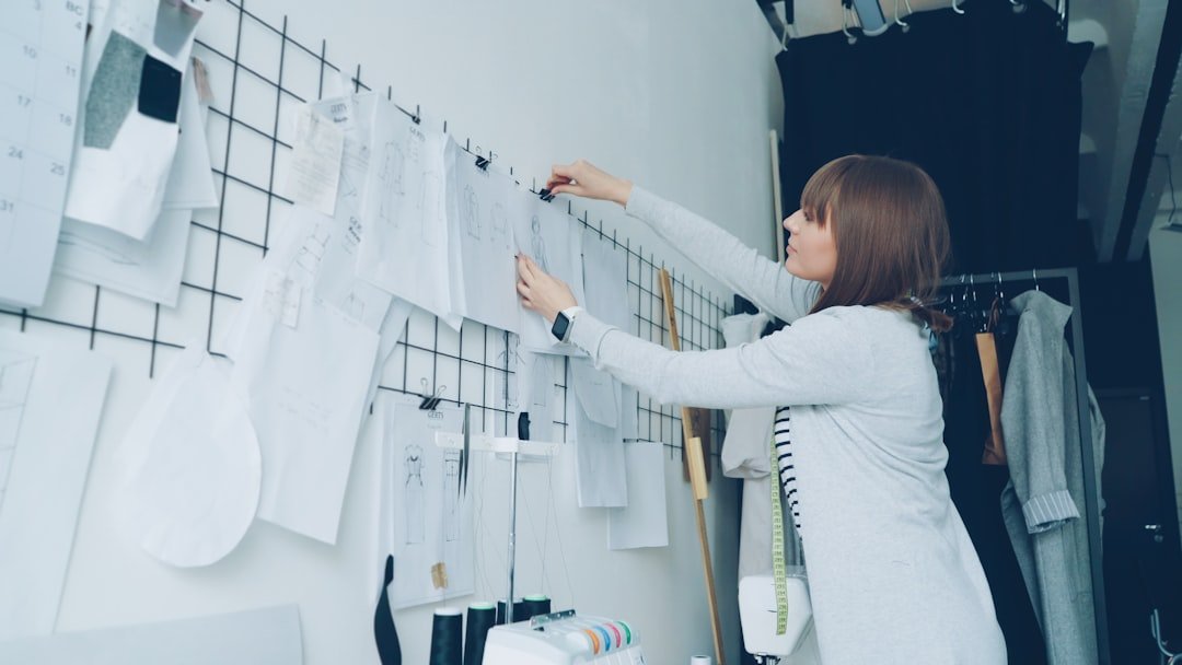 A fashion designer is arranging sketches on the wall